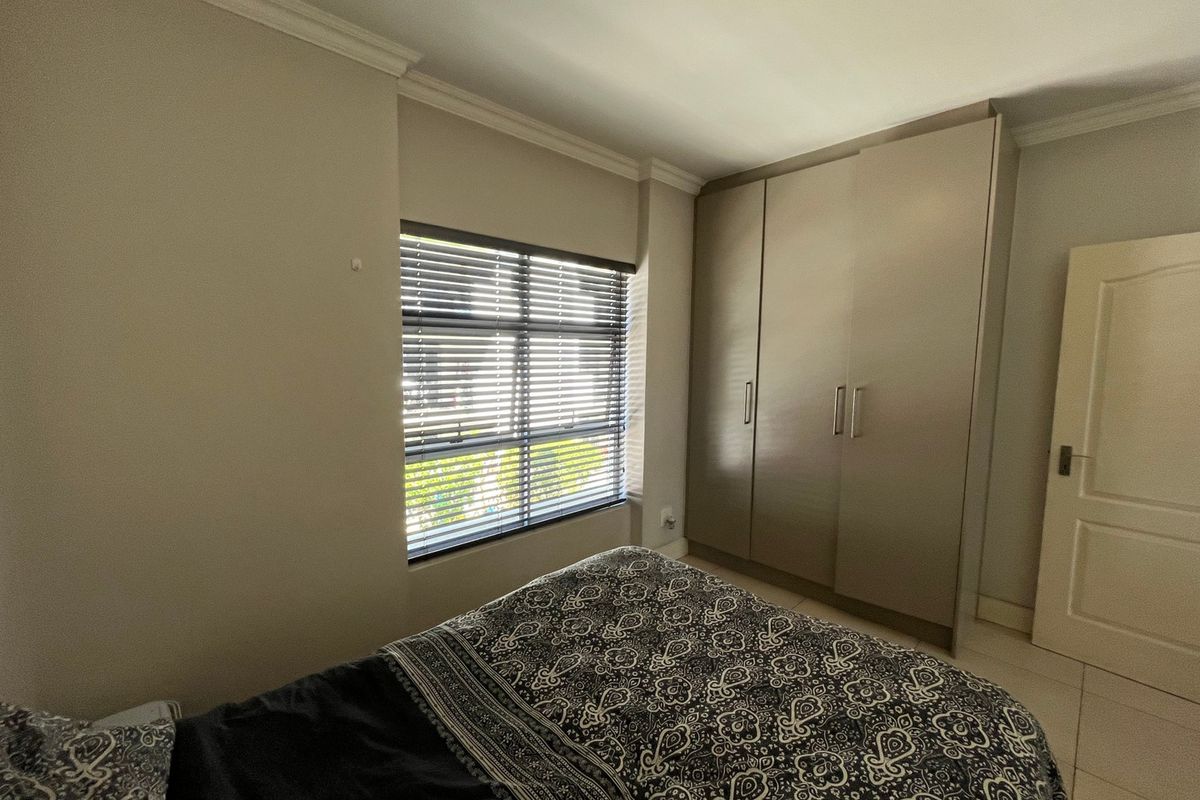 A well-maintained bedroom featuring neutral walls, tiled flooring, coving, and a large built-in wardrobe with modern finishes.