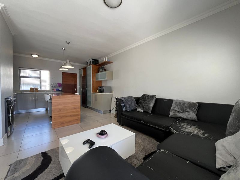 Open-plan living area featuring a modern kitchen with island, tiled flooring, and neutral wall finishes, creating a functional and connected living space.