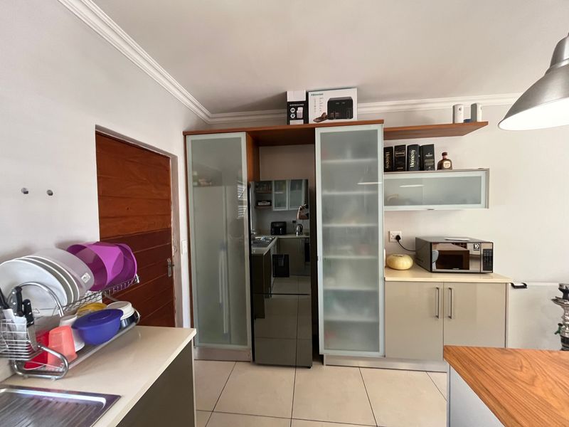 A functional kitchen featuring built-in cabinetry with frosted glass accents, tiled flooring, and ample counter space for meal preparation.