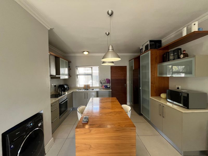A functional kitchen featuring built-in cabinetry, a central wooden island, tiled flooring, and integrated appliances, offering a practical layout for cooking and dining.
