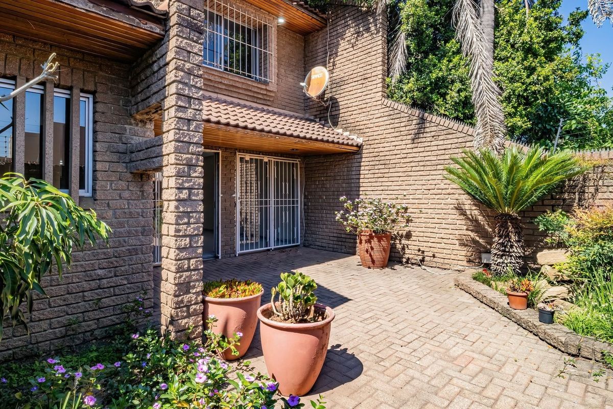 A private rear patio area featuring face brick construction, paved flooring, and secure access points, complemented by established garden landscaping.