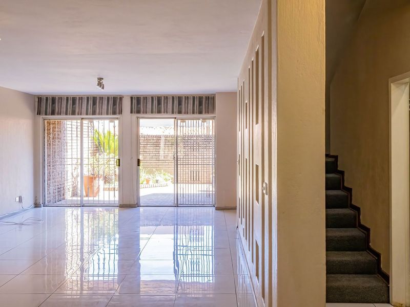 Spacious open-plan living area featuring polished tiled floors, modern ceiling lighting, and sliding glass doors leading to an outdoor patio area.