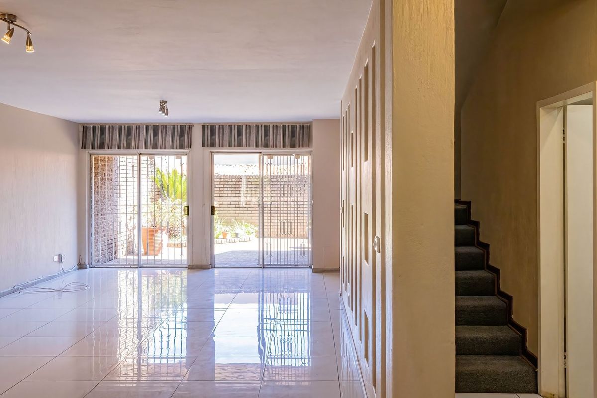 Spacious open-plan living area featuring polished tiled floors, modern ceiling lighting, and sliding glass doors leading to an outdoor patio area.