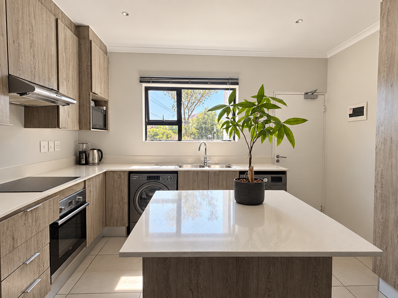 Modern kitchen featuring wood-grain cabinetry, stone countertops, a central island, and integrated appliances, offering a clean and functional culinary space.
