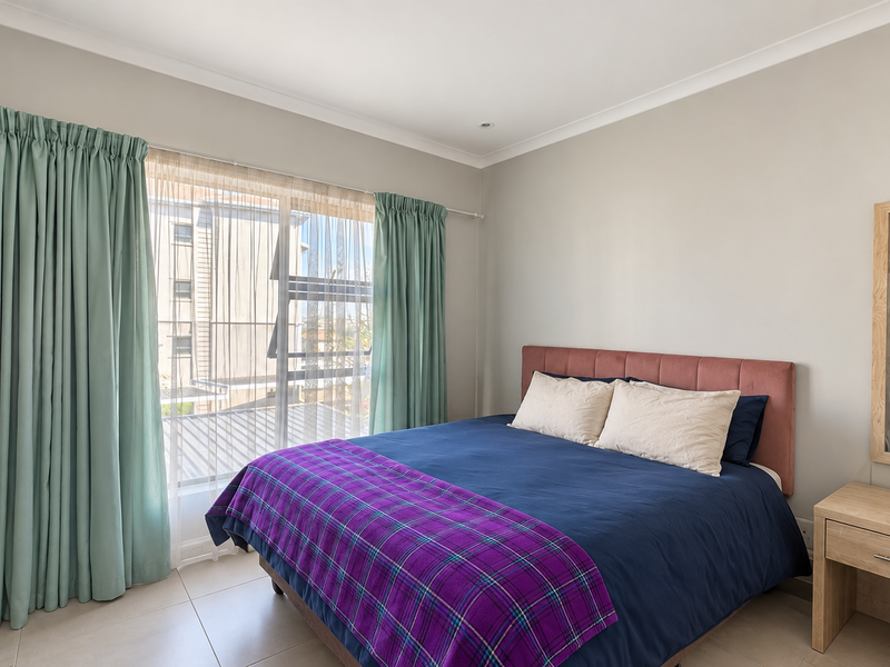 A well-maintained bedroom featuring tiled flooring, built-in wardrobe storage, and large windows with curtains, offering a bright and functional living space.