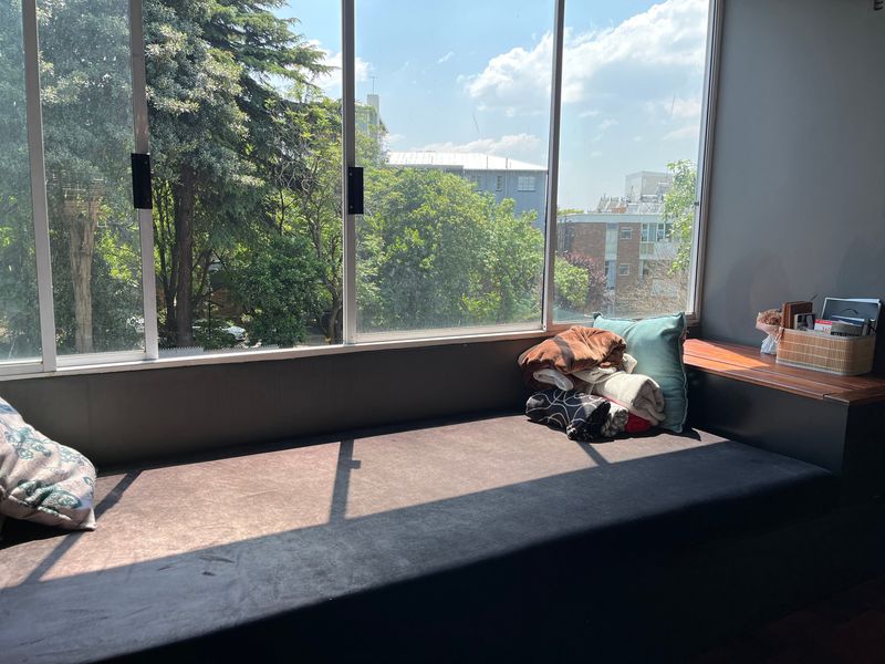 A bright living area featuring a large window with a built-in window seat and wooden ledge, offering pleasant neighborhood views.