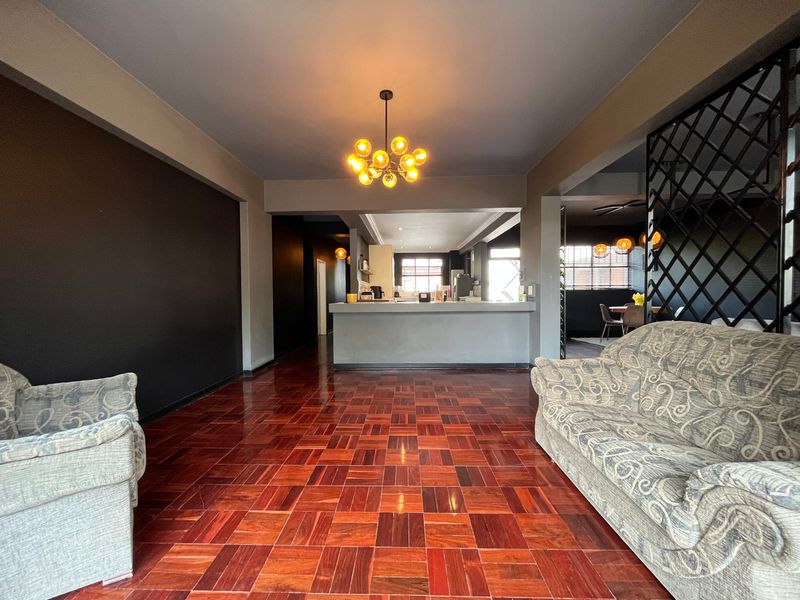 Open plan living and kitchen area featuring polished parquet flooring, a central breakfast bar, and decorative metal room divider.