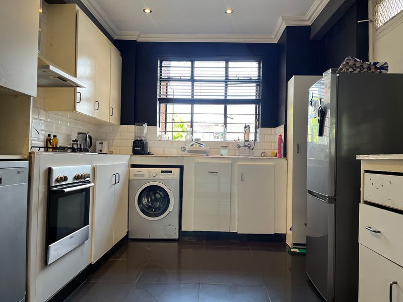 A functional kitchen featuring subway tile backsplash, built-in cabinetry, stainless steel oven, and integrated sink with dark tiled flooring and modern recessed lighting.