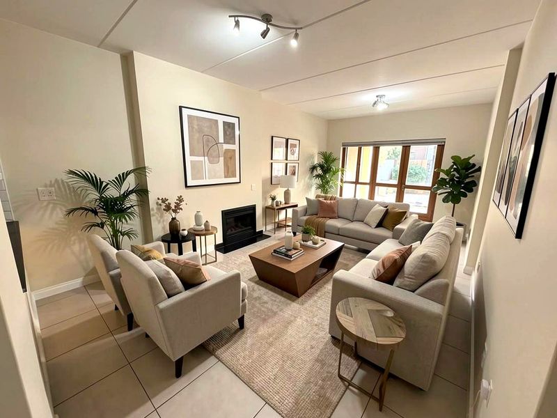 A well-lit living room featuring tiled flooring, a built-in fireplace, and large windows that provide ample natural light.