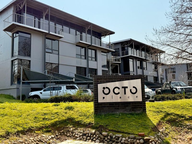 Front view of Octo Place office complex featuring modern multi-story architecture, balconies, and dedicated shaded parking areas.