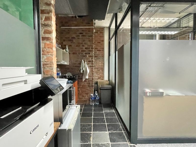 Office space featuring exposed brickwork, stone tile flooring, and modern glass partitioning, providing a contemporary industrial aesthetic.