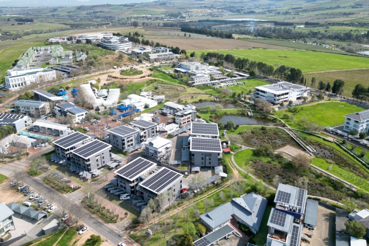 Aerial view of a modern office park complex featuring multiple buildings with rooftop solar installations, landscaped grounds, and integrated parking facilities.