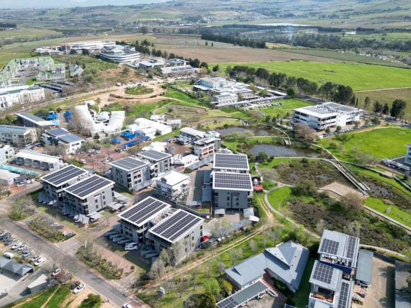 Aerial view of a modern office park complex featuring multiple buildings with rooftop solar installations, landscaped grounds, and integrated parking facilities.