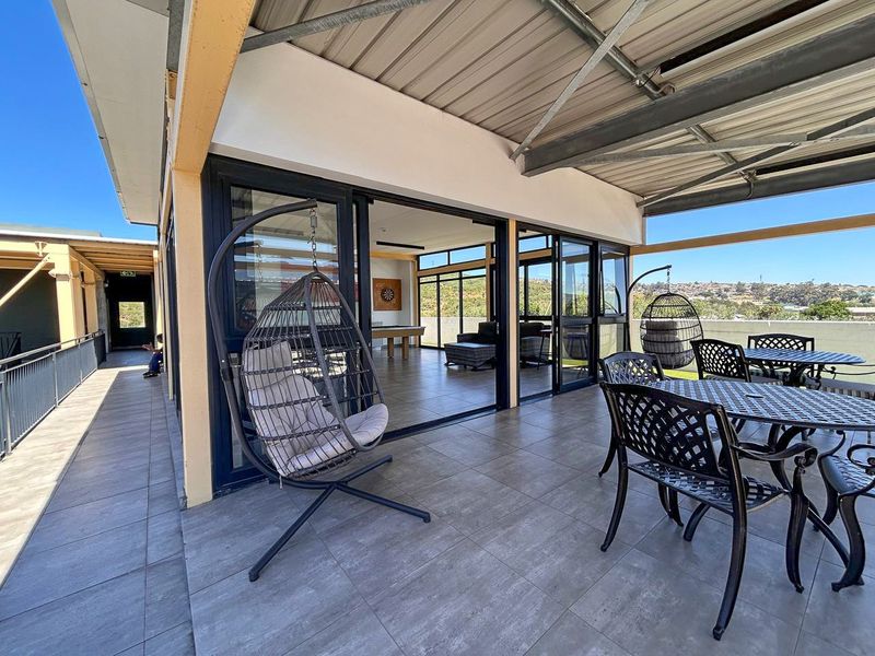 Spacious covered balcony featuring tiled flooring, metal roofing, and large sliding glass doors providing seamless access to the interior living area.