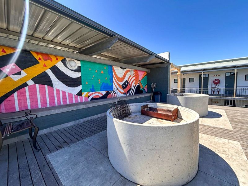 Outdoor patio area featuring built-in concrete braai facilities, timber decking, and a covered section with a decorative mural wall.