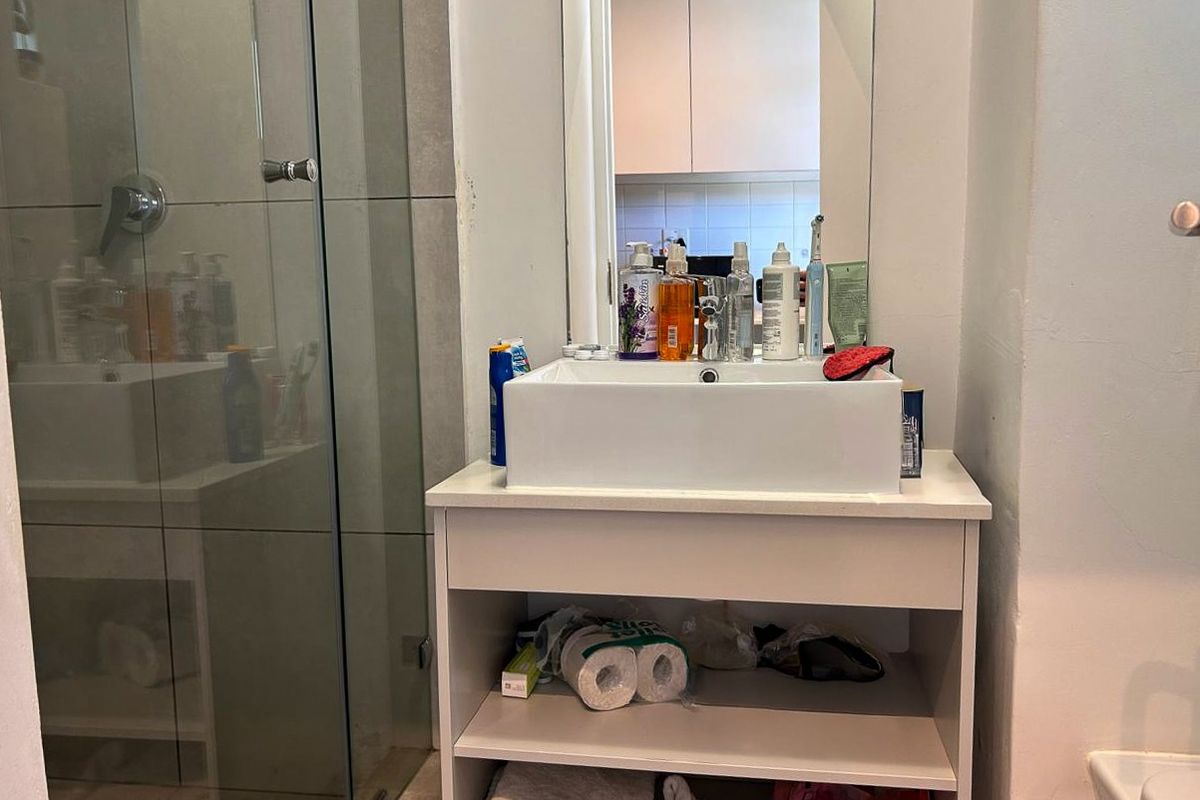 A compact bathroom featuring a modern vessel sink on a vanity cabinet, a glass-enclosed shower, and a wall-mounted mirror.