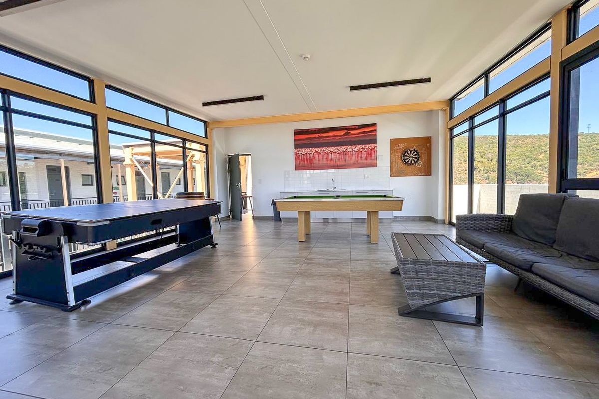 Spacious, light-filled living area featuring large format floor tiles and extensive floor-to-ceiling windows with views, including a built-in sink area.