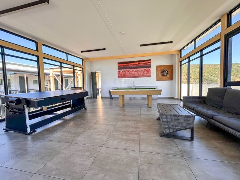 Spacious, light-filled living area featuring large format floor tiles and extensive floor-to-ceiling windows with views, including a built-in sink area.