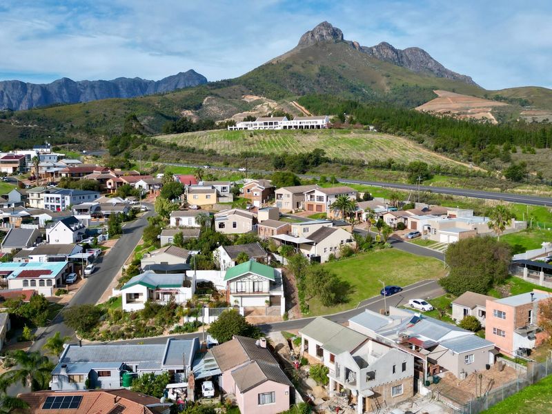 An aerial view of a residential neighborhood set against a scenic mountain landscape, showcasing the property's location and surrounding community infrastructure.