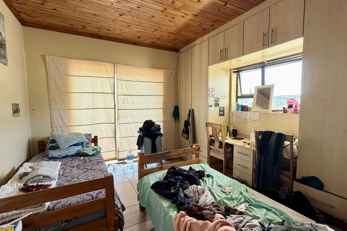 A bedroom featuring built-in cupboards, a built-in desk, tiled flooring, and a timber ceiling, offering functional storage and workspace.