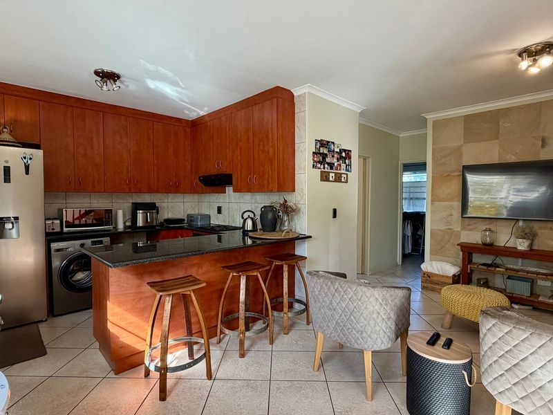 Open-plan living area featuring a kitchen with wooden cabinetry, granite countertops, and a stone-clad feature wall in the lounge area.