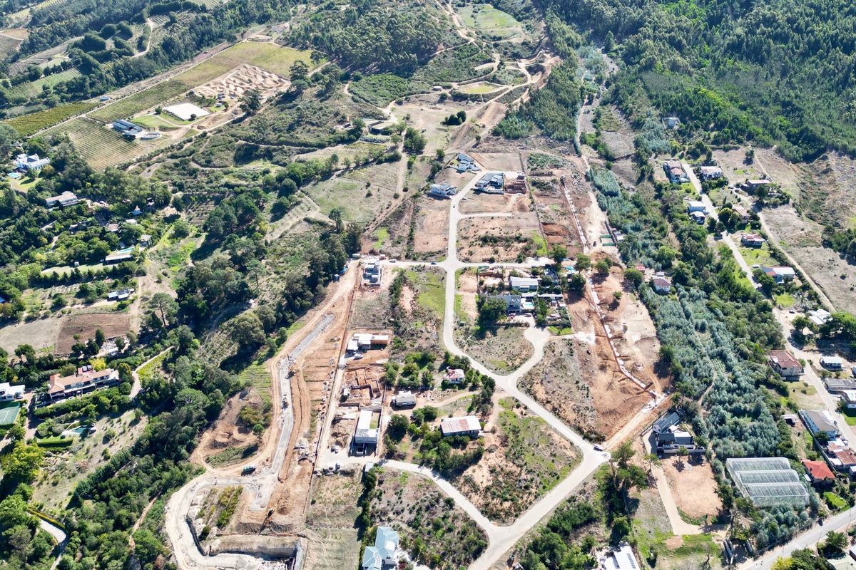 An aerial view of a residential development site showing established road networks, cleared plots, and surrounding natural landscape.