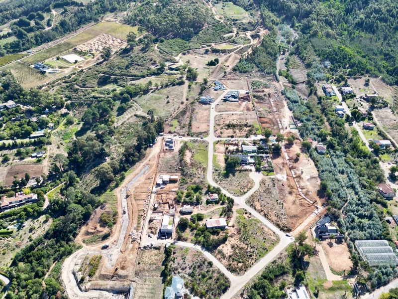 An aerial view of a residential development site showing established road networks, cleared plots, and surrounding natural landscape.