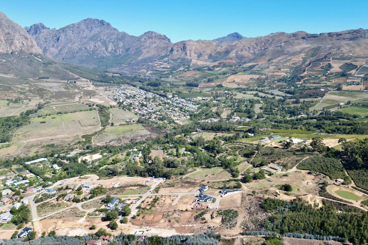 An expansive aerial view of a residential development nestled in a scenic valley, surrounded by mountains and natural landscape.