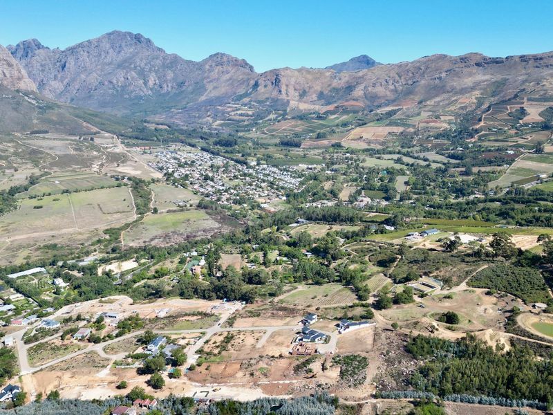 An expansive aerial view of a residential development nestled in a scenic valley, surrounded by mountains and natural landscape.