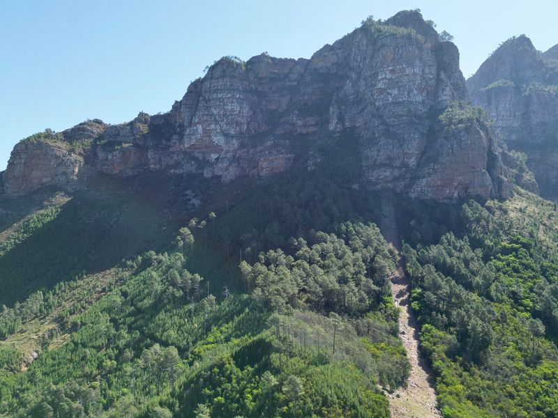 A scenic view of a rugged mountain range with dense forest vegetation and natural rock formations.