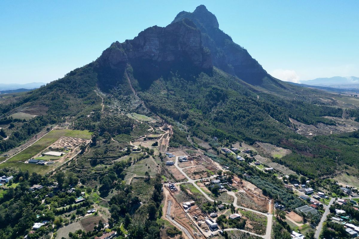 An aerial view of a residential development area situated at the base of a prominent mountain range.