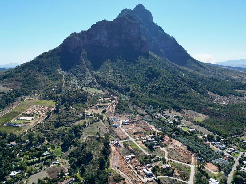 An aerial view of a residential development area situated at the base of a prominent mountain range.