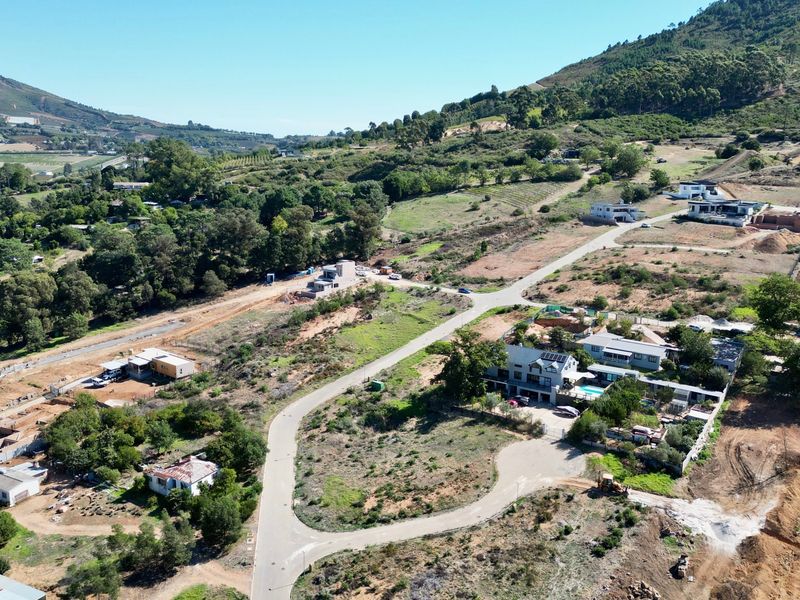 Aerial view of a residential development area featuring paved roads, established properties, and surrounding mountainous landscape.