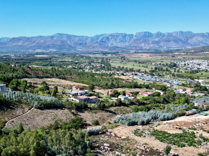 An expansive aerial view of a residential area nestled in a valley with a prominent mountain range in the background.