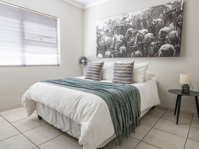 A well-maintained bedroom featuring neutral tiled flooring and venetian blinds, offering a clean and comfortable living space.