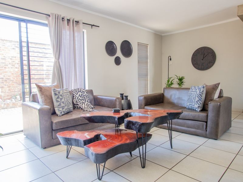 A bright and well-maintained living room featuring ceramic floor tiles and a large sliding glass door providing access to the exterior.