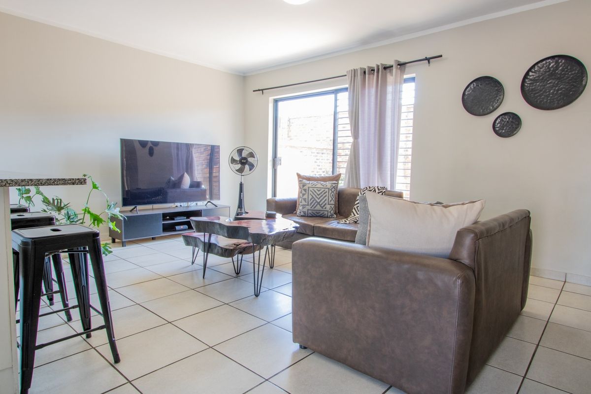 A bright living room featuring tiled flooring and a large sliding glass door providing natural light and access to the exterior.