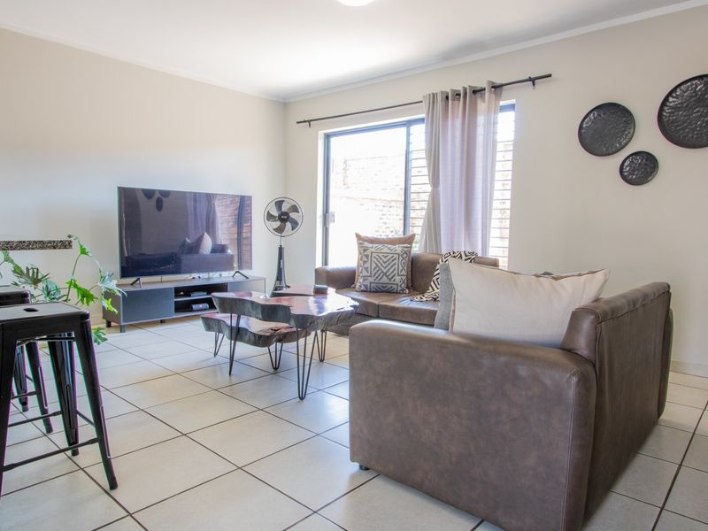 A bright living room featuring tiled flooring and a large sliding glass door providing natural light and access to the exterior.