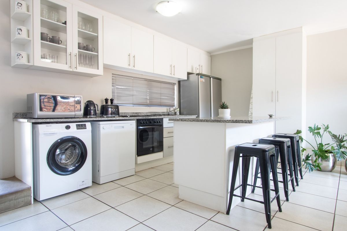 A well-maintained kitchen featuring white cabinetry, granite countertops, a central island, and integrated appliance spaces with tiled flooring.