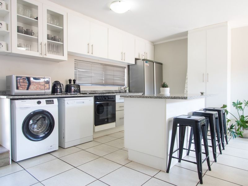 A well-maintained kitchen featuring white cabinetry, granite countertops, a central island, and integrated appliance spaces with tiled flooring.