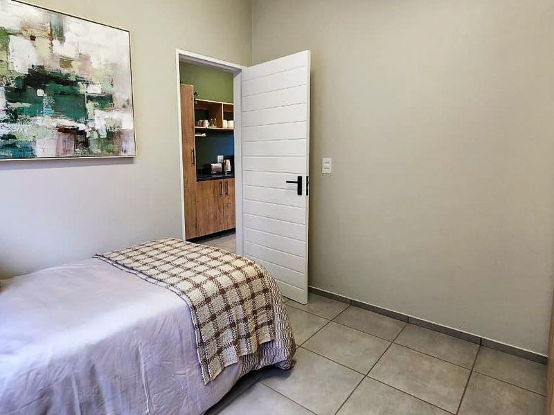 A well-maintained bedroom featuring tiled flooring, a built-in wardrobe, and direct access to an adjacent kitchen area.
