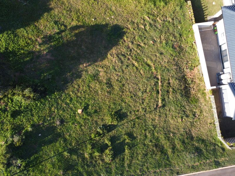 An aerial view of a vacant residential plot of land adjacent to an existing property.