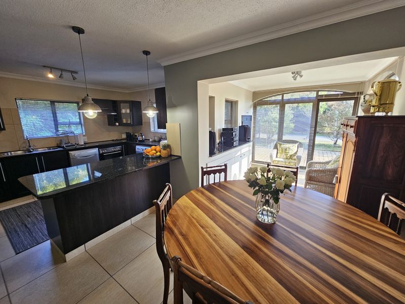 Open-plan kitchen and dining area featuring dark cabinetry, granite countertops, tiled floors, and direct access to a patio through sliding glass doors.