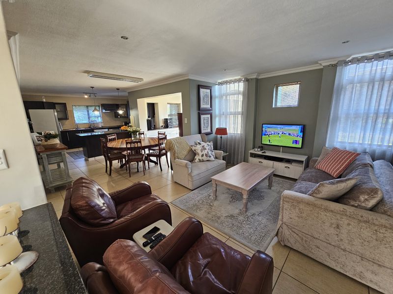 Spacious open-plan living area featuring a combined lounge, dining space, and kitchen with tiled flooring and modern cabinetry.