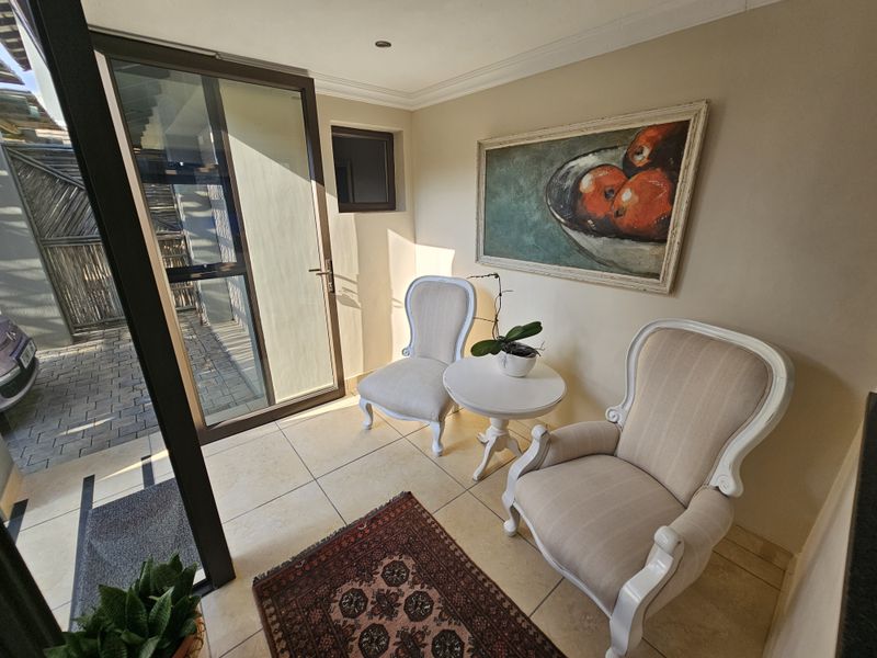 A bright and welcoming entrance area featuring tiled flooring, modern cornicing, and a large glass door providing direct access to the exterior.