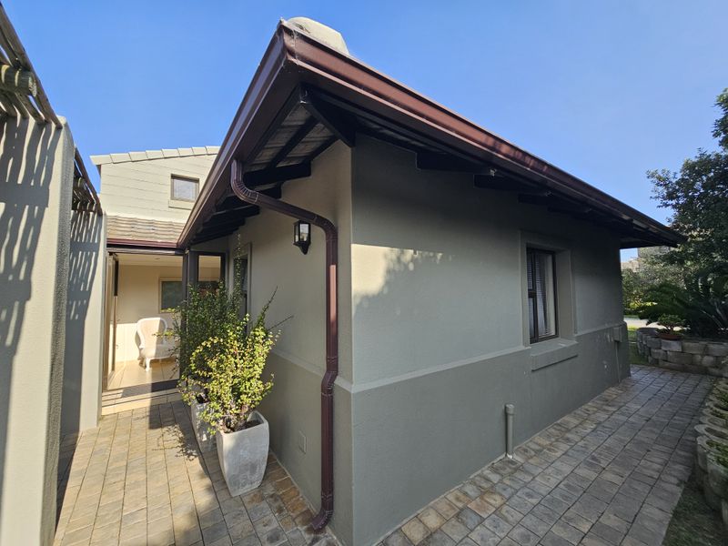 A view of the rear exterior facade featuring paved patio flooring, guttering, and exterior wall lighting.