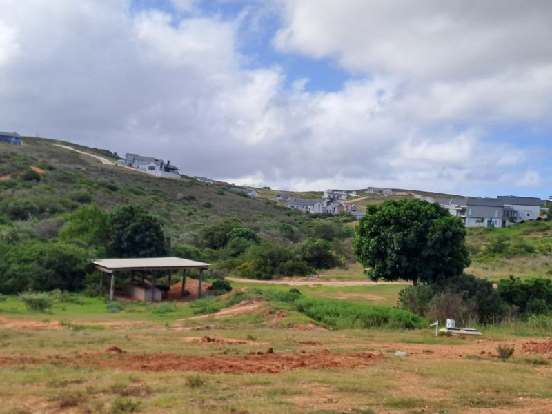 A scenic view of the surrounding landscape and hillside residential development, featuring natural vegetation and an open outdoor structure.