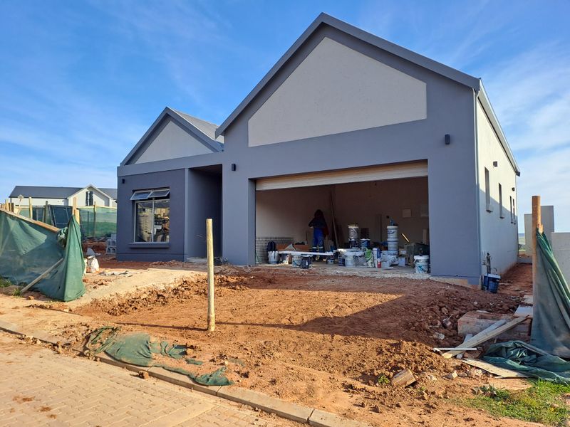 Front view of a modern house under construction, featuring a double garage and unfinished landscaping.