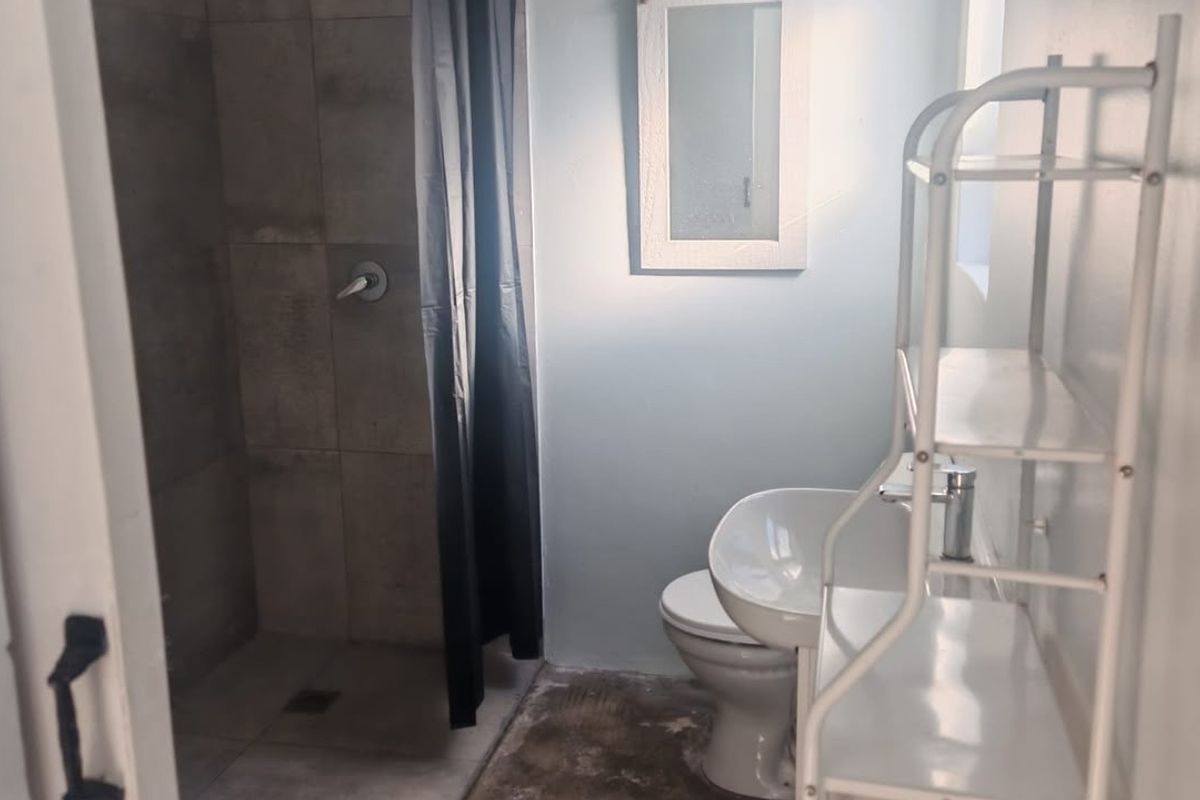 A functional bathroom featuring a tiled shower enclosure, pedestal basin, and toilet, with a neutral color palette.