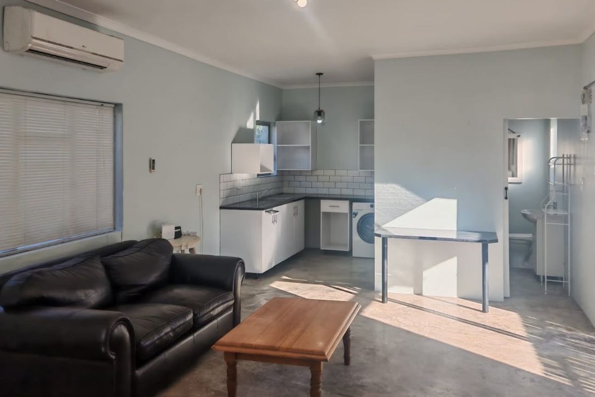 Open-plan living area featuring a compact kitchen with subway tile backsplash, built-in cabinetry, and direct access to an adjacent bathroom.